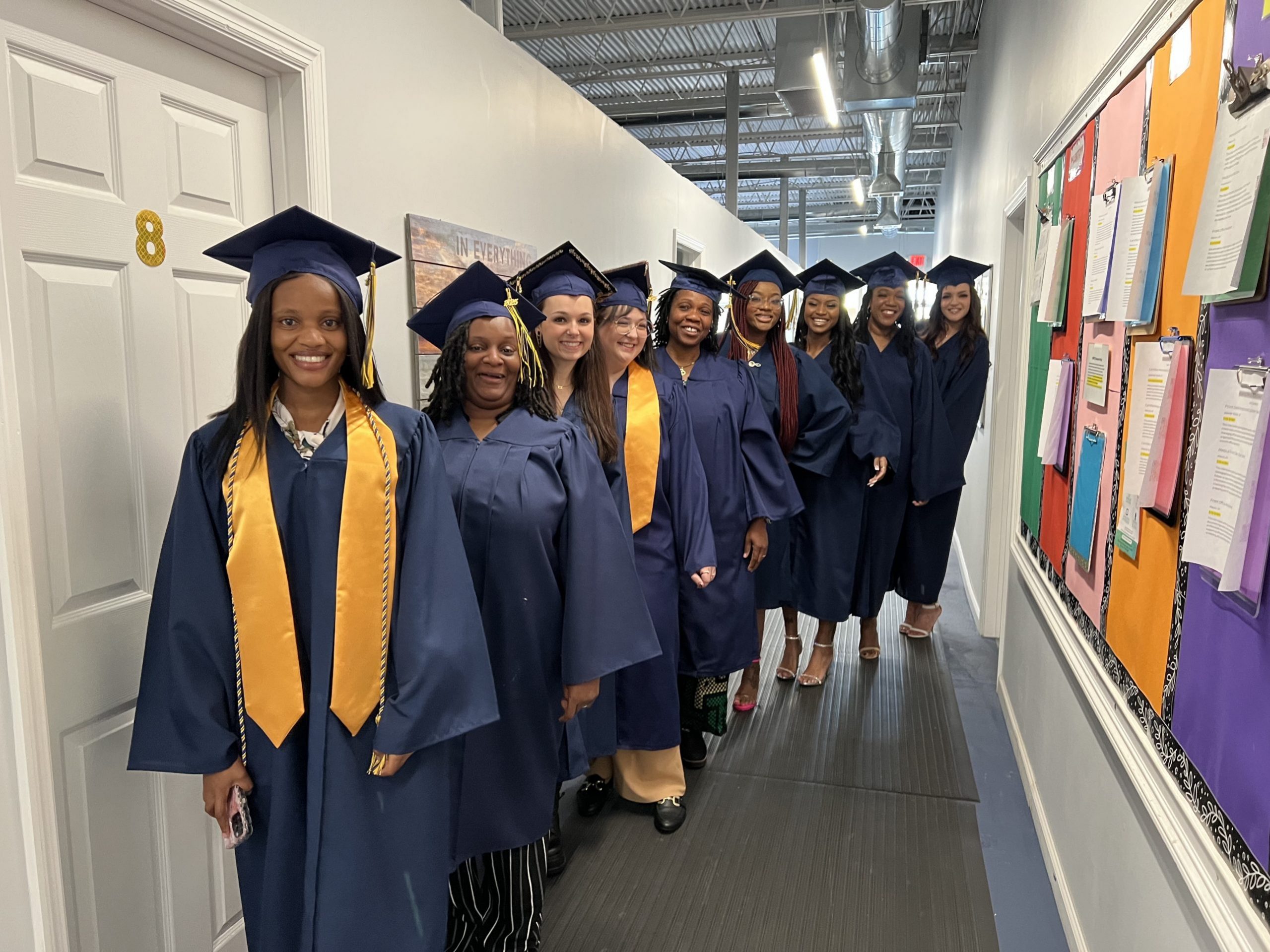 Graduates in caps and gowns lined up smiling at the camera