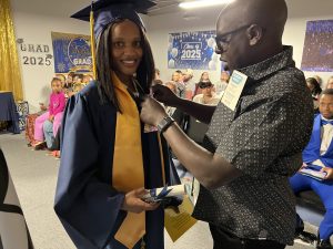 A graduate having something pinned on her gown by a man