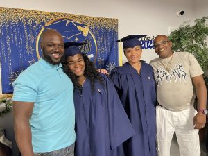 Two female graduates posing and smiling with two males